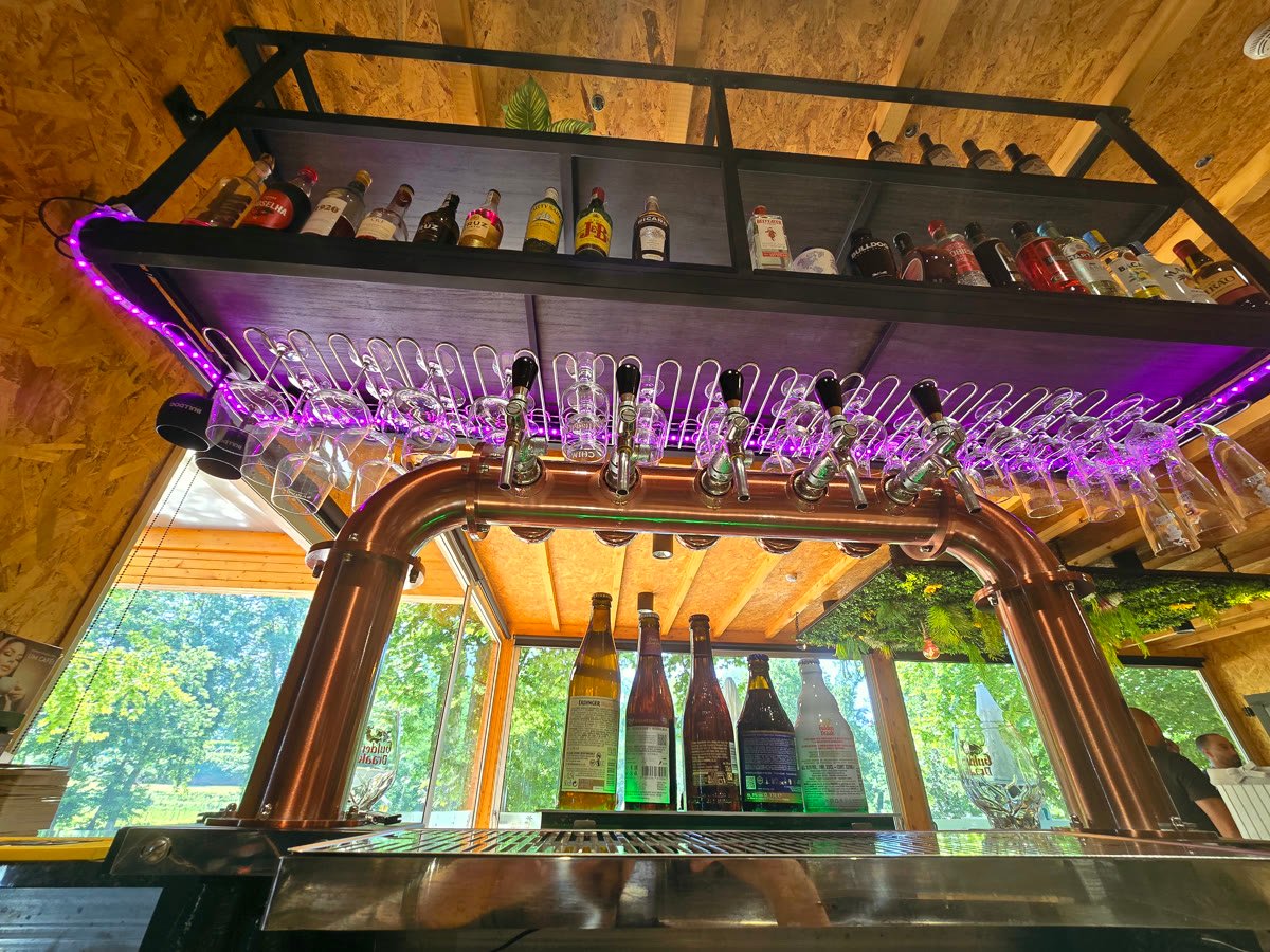 Bar de cobre com torneiras de cerveja, copos e vista para o parque
