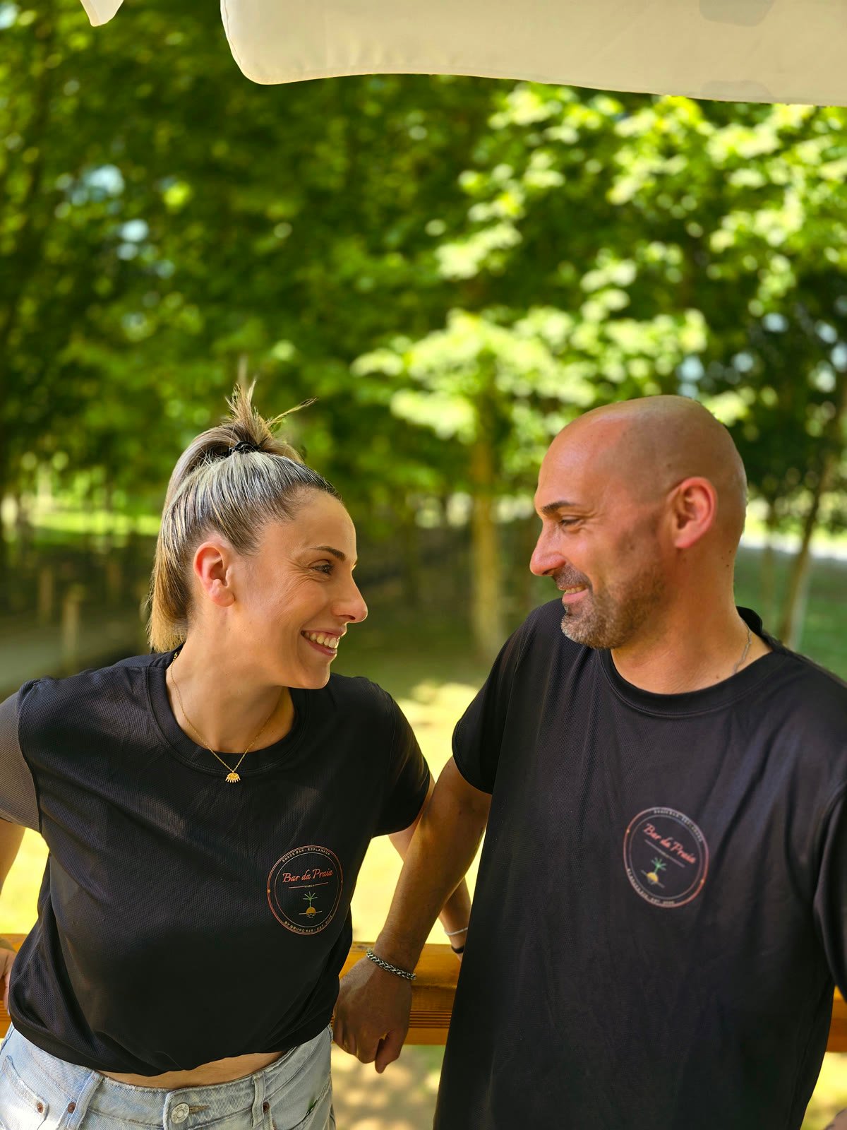 Daniela e Pedro, fundadores do Bar da Praia, a rir juntos na esplanada junto ao parque
